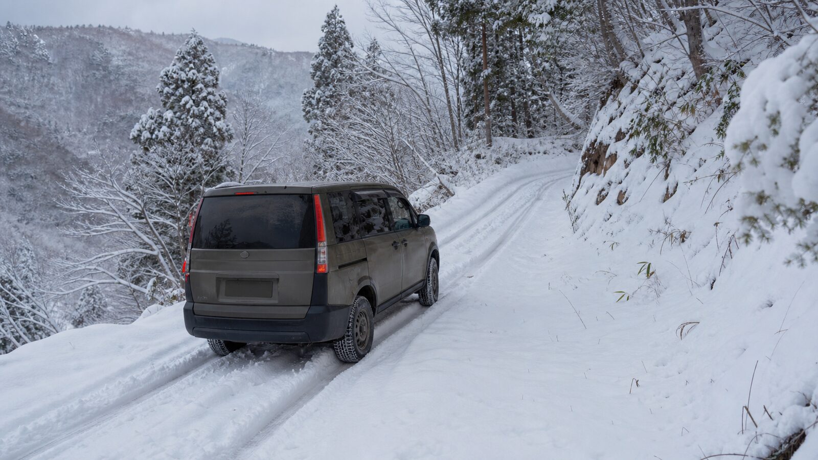雪道の坂を慎重に進むミニバンと4WDロックの使いどころを示すイメージ