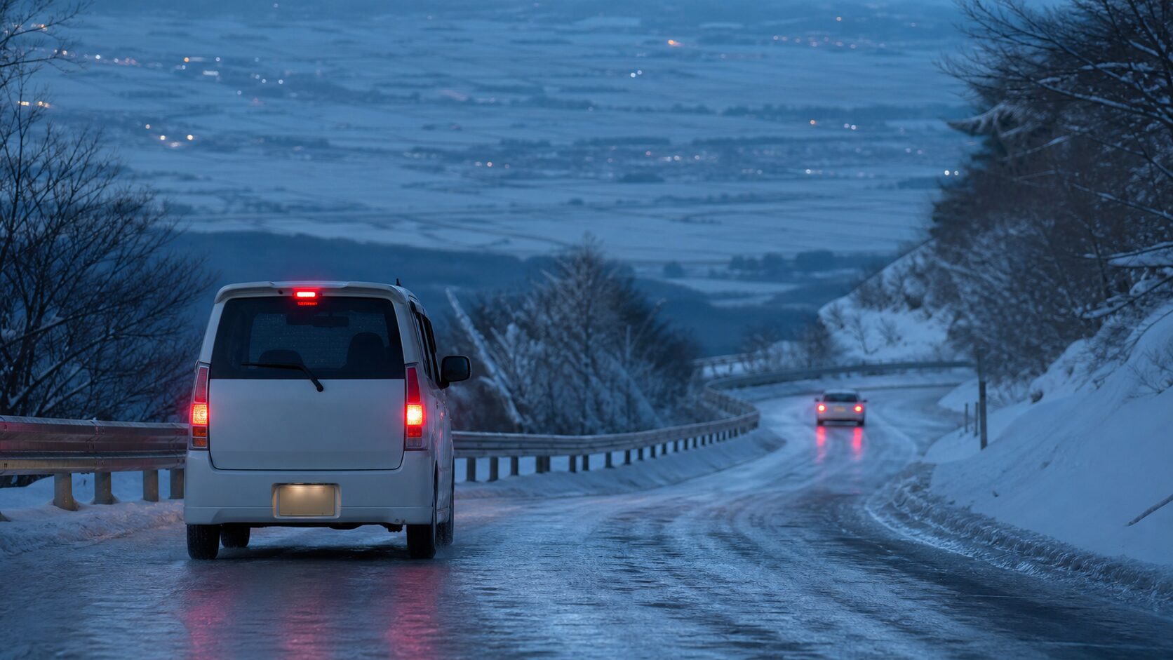凍結した下り坂で車間距離を取りながら慎重に走る軽スーパーハイトワゴン